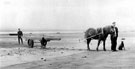 View: c02996 Heswall: Bringing a punt up the beach 	